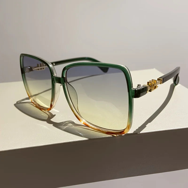 Retro two-tone gradient sunglasses with green and amber lenses resting on a white surface.