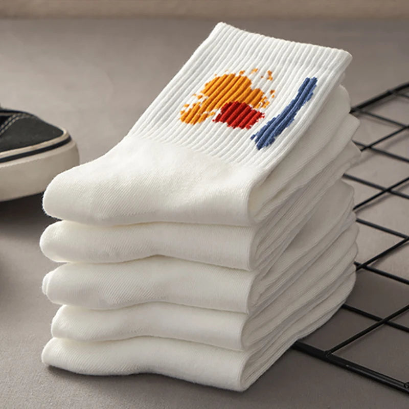 A stack of white breathable cotton socks with orange and blue designs resting on a black wire grid.