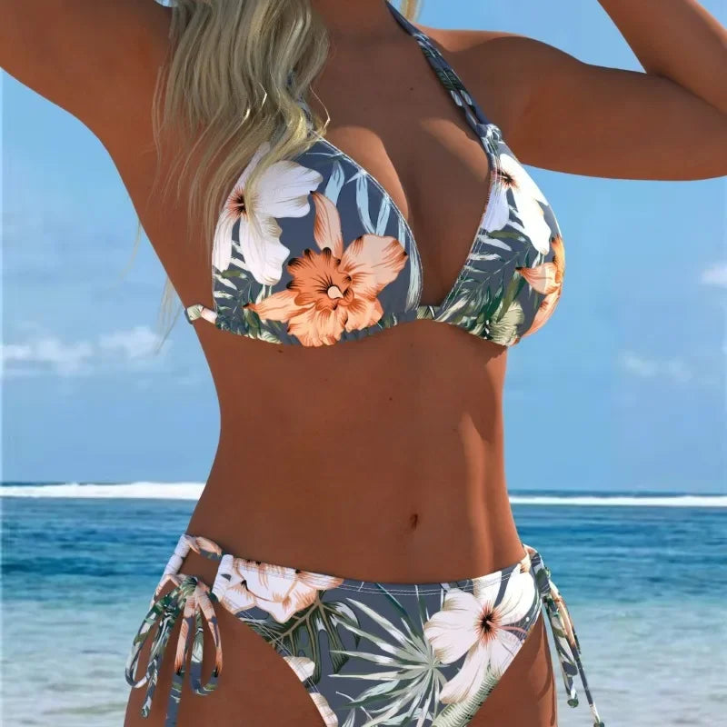 A woman wearing a floral print two-piece bikini swimsuit on a beach.