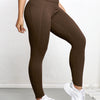 A woman wearing high-waisted brown sports leggings and white sneakers.