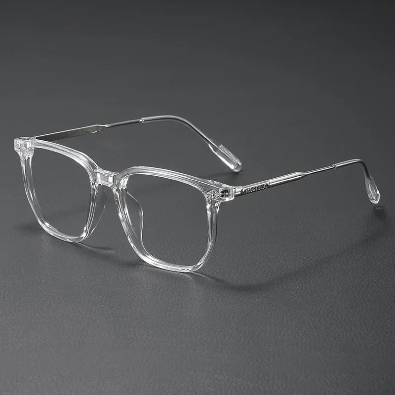 Clear acetate eyeglasses with thin metal temples resting on a dark surface.