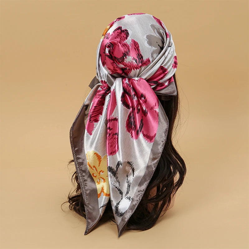A pink and gray satin square scarf tied around a person's dark hair.
