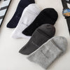 A collection of five men's bamboo fiber socks in various colors including black, white, and gray, laid out on a white surface