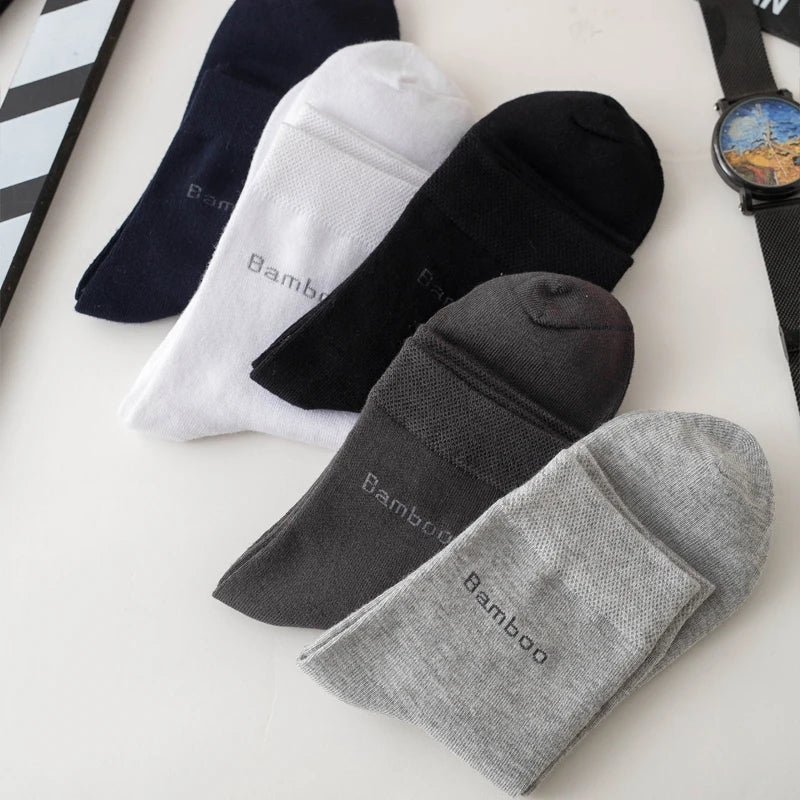 A collection of five men's bamboo fiber socks in various colors including black, white, and gray, laid out on a white surface
