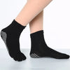 Black yoga socks with white polka dots worn on a foot.