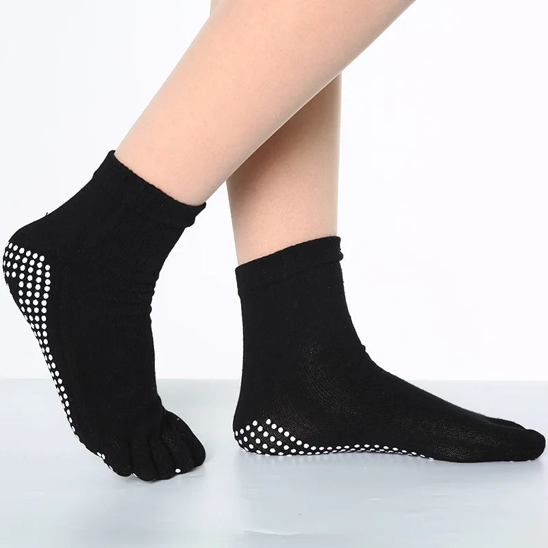 Black yoga socks with white polka dots worn on a foot.