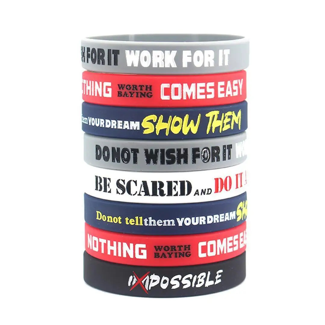 Pila de pulseras de silicona coloridas con frases motivacionales como FOR IT WORK FOR IT y SHOW THEM