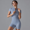 A woman models a light blue seamless yoga jumpsuit, showing the front zipper detail.