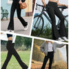 A woman models black flared yoga trousers paired with a white top and boots outdoors.