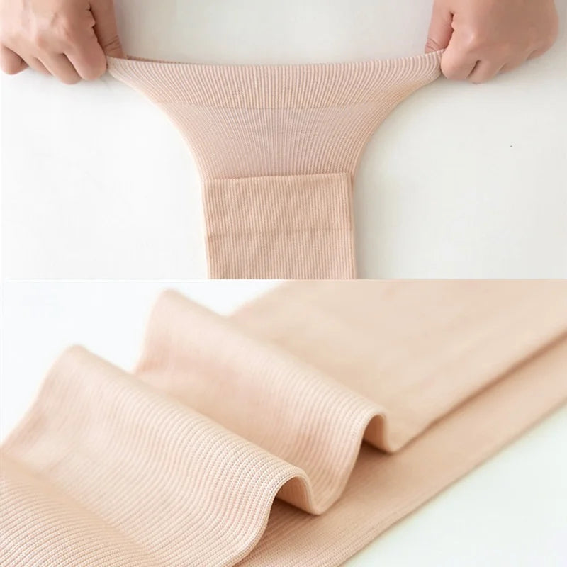 A pair of beige compression thigh high socks being held by hands, showing the texture and fit.
