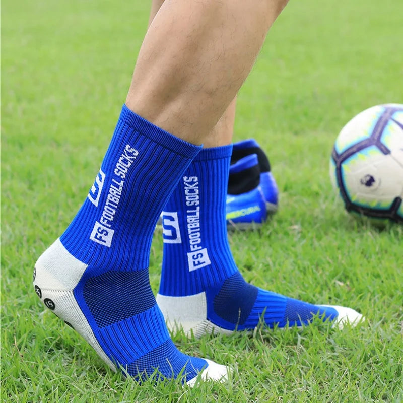 A close-up of blue and white athletic soccer socks worn by a person on a green field.
