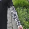 Close-up of a person wearing black clothing with an arm covered in detailed black and white tattoo sleeves for sun protection