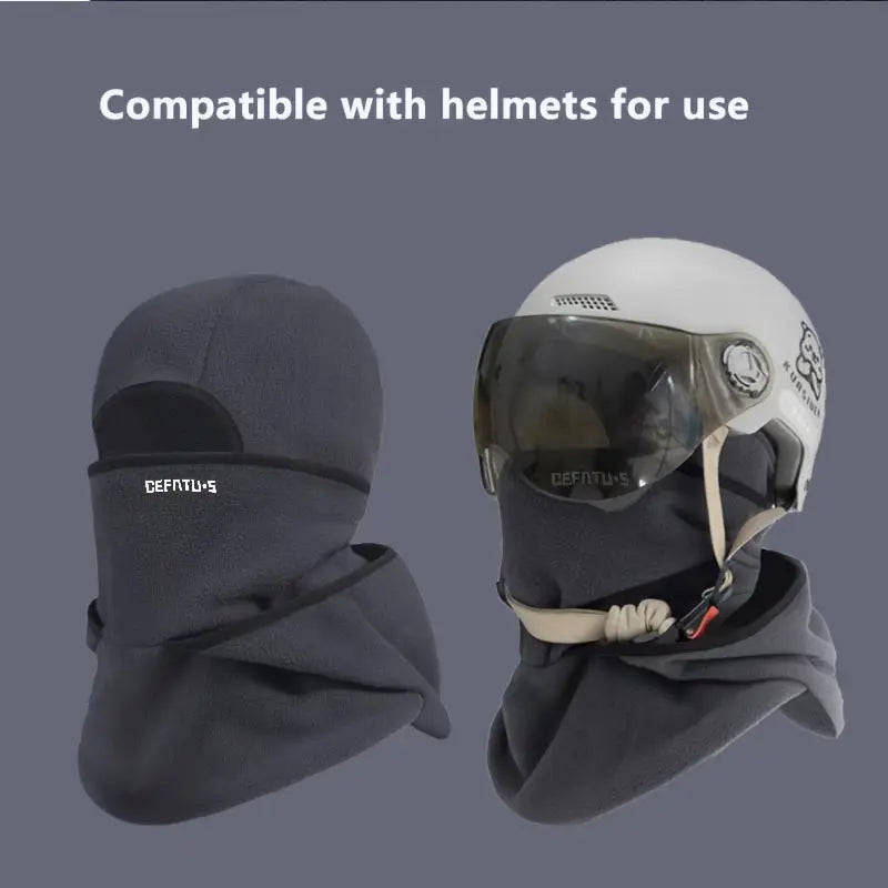 A dark gray double-layer winter beanie with a clear visor is shown next to a white helmet.
