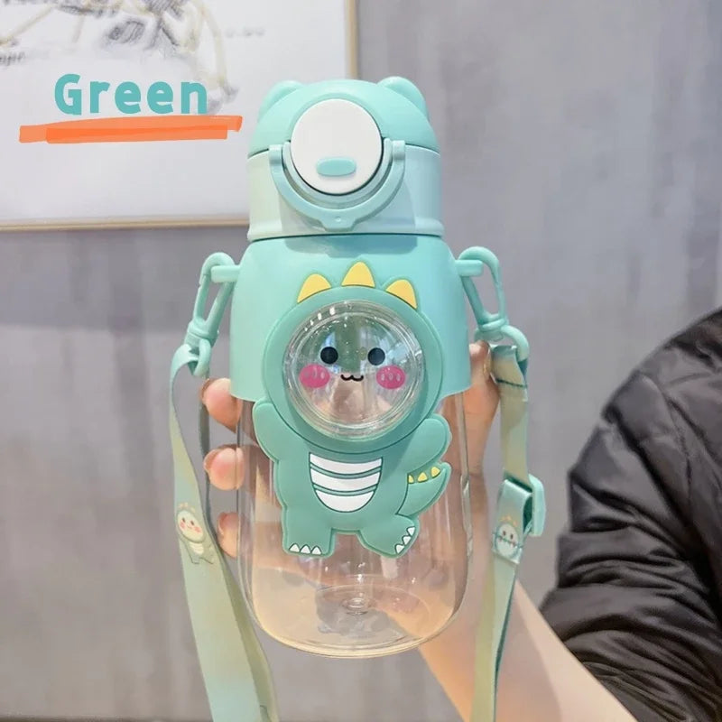 A hand holds a leak-proof cartoon dinosaur water bottle in mint green with a light blue lid and strap.