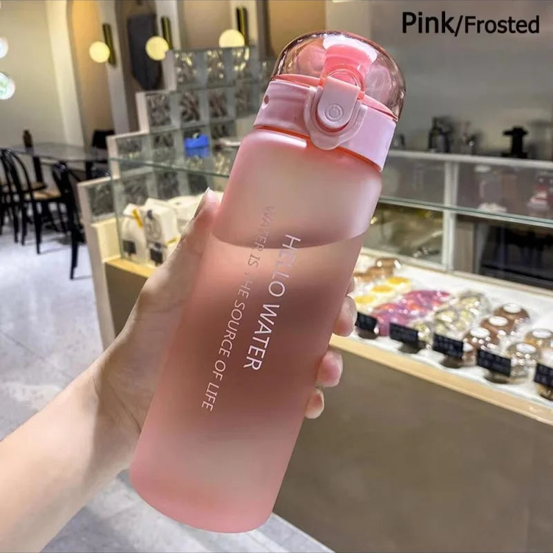 Eine rosa gefrorene, dichte Sportflasche wird in einer Hand vor einem unscharfen Hintergrund gehalten.