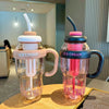 Two glass-like containers filled with pink ice cream served in plastic sports water bottles with straws