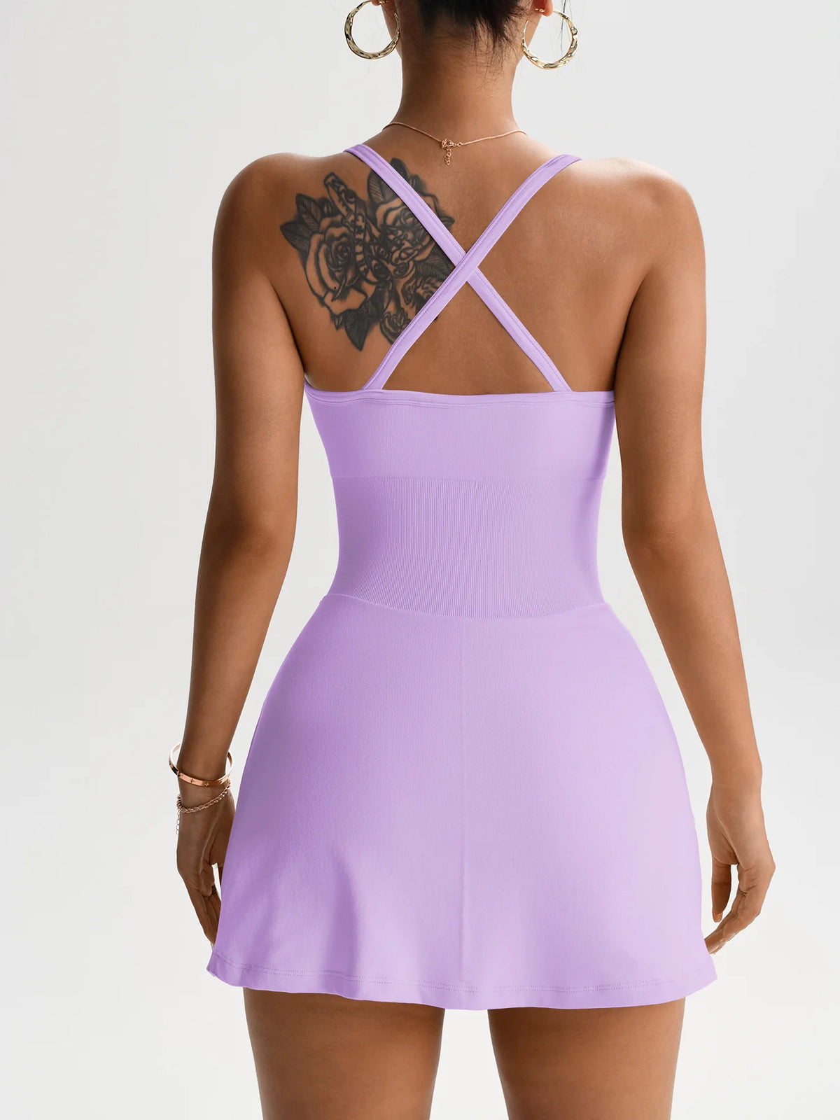 Lila Tennis-Skortkleid mit Kreuzriemen-Design, getragen von einem Model.