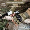 A close-up of olive green protective training gloves with a flexible grip, shown in an outdoor setting.