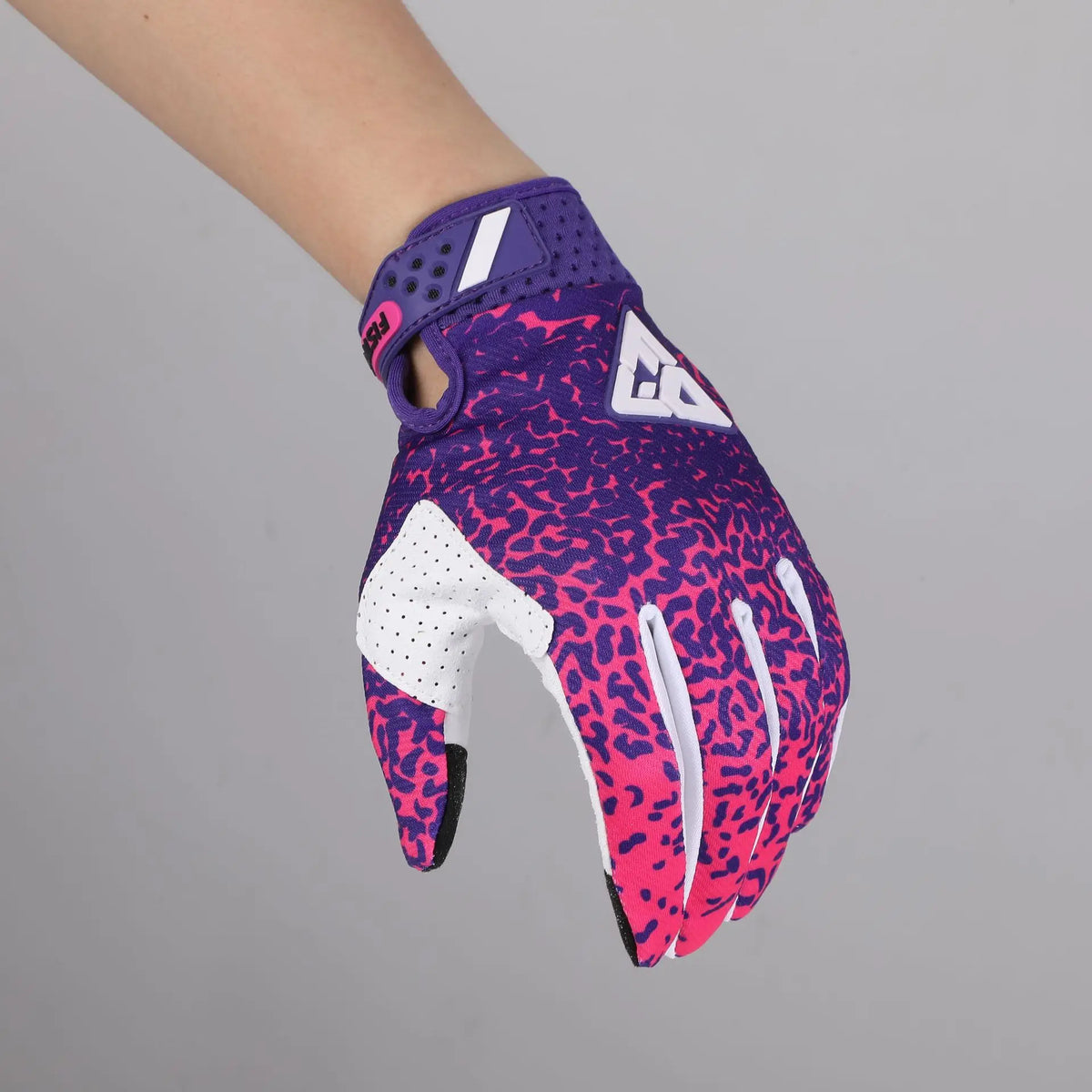 A close-up of full finger motocross gloves in purple and pink leopard print with white accents.