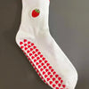 Weiße Strick-Yoga-Socken mit roter Erdbeere und Herzmuster am Fuß.