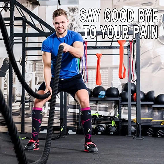 A muscular man in a blue shirt and black shorts is performing a heavy pull-up exercise using thick black ropes in a gym setti