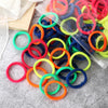 A pile of 50 mixed color elastic hair bands in various shades of orange, red, yellow, green, and blue.