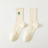 A pair of cream-colored men's athletic crew socks with a green embroidered design on the ankle.