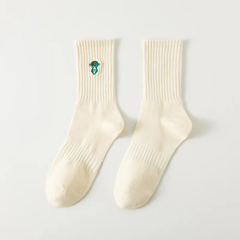 A pair of cream-colored men's athletic crew socks with a green embroidered design on the ankle.