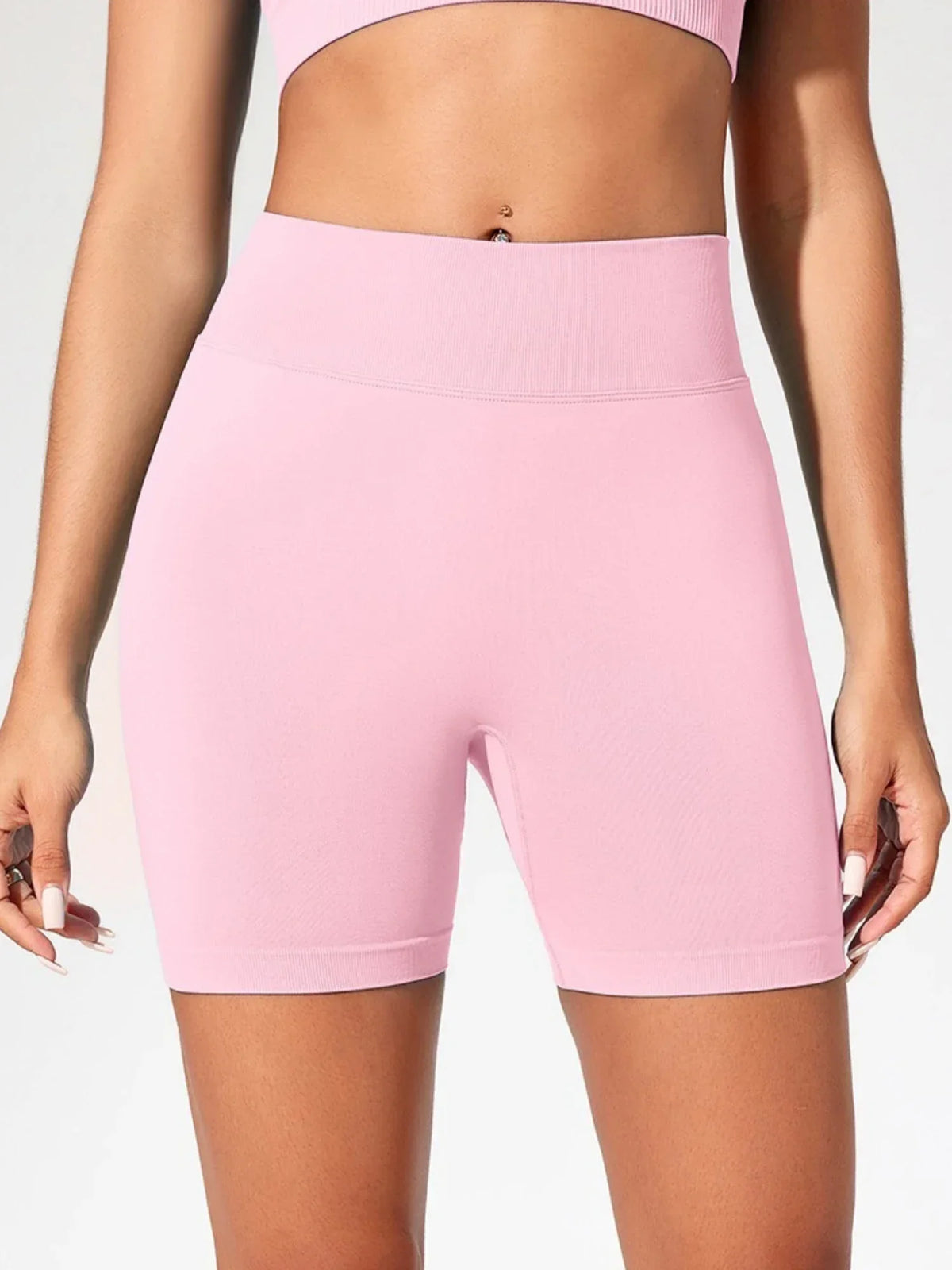 A model is wearing light pink high-waisted yoga shorts.