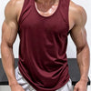 A muscular man wearing a maroon sleeveless tank top and light gray athletic shorts.
