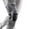 A close-up of a black and silver copper ions infused knee brace worn on a person's leg.