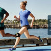 Two people running outdoors demonstrating the use of a patella knee strap for support.
