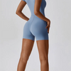 A woman wearing a light blue seamless yoga jumpsuit, shown from the side.