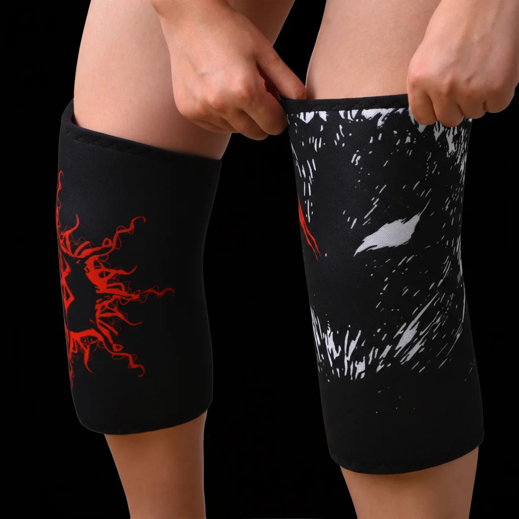 Une personne porte des genouillères de levage noires avec des motifs graphiques rouges sur les jambes.