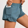 A model wears teal athletic shorts with mesh pockets and a drawstring detail.