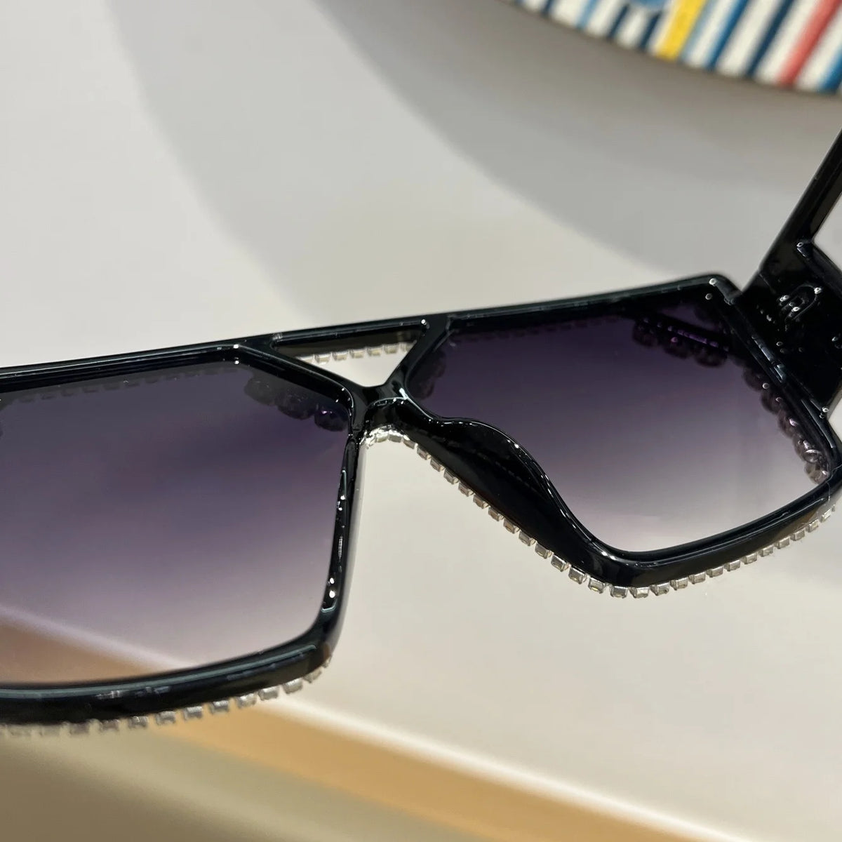 A close-up view of black geometric fashion sunglasses with clear rhinestone detailing.