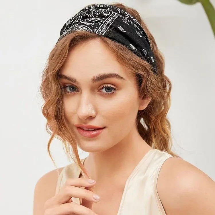 A woman wearing a black bohemian print wide headband while posing for a photo.