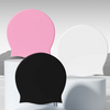 Extra large swimming cap shown in pink, black, and white on display stands.