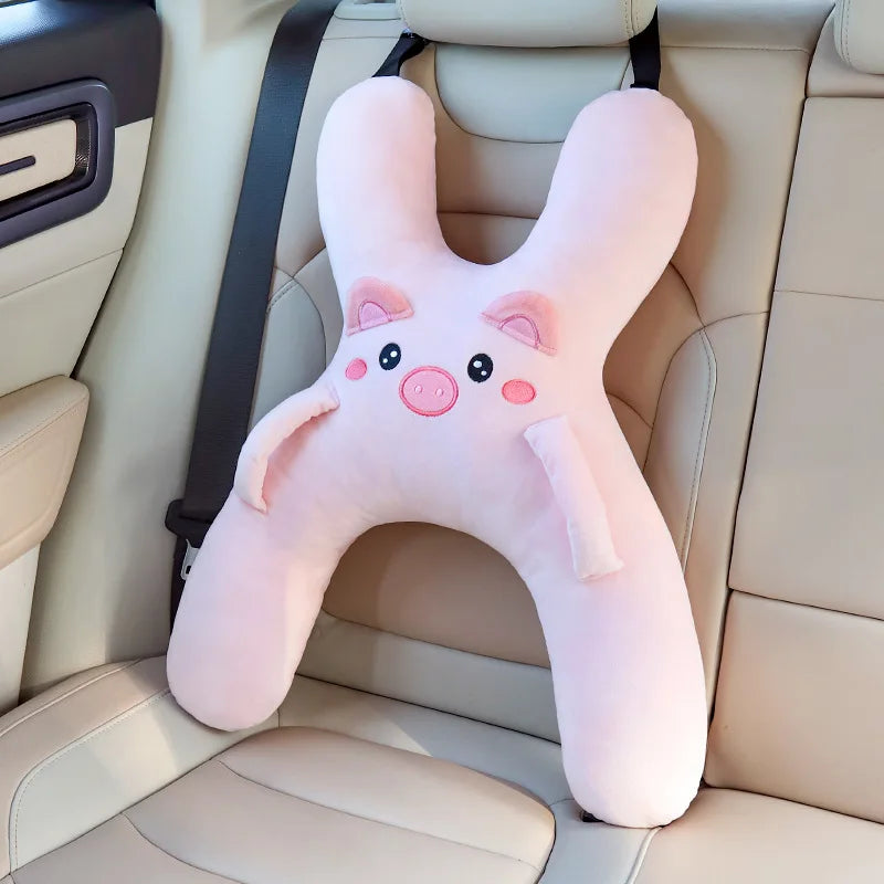 Un coussin de cou car en forme de porc rose posé sur un siège de voiture de couleur claire.