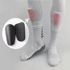 Un paire de protège-tibias de football blancs avec rembourrage rose sur une jambe, à côté de protections d'entraînement noire
