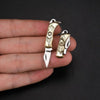 Una mano sostiene un mini cuchillo llavero plegable de latón con hoja de plata y detalles dorados.