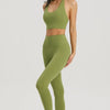 A woman models a olive green halter neck yoga and gym sports bra top and matching leggings.