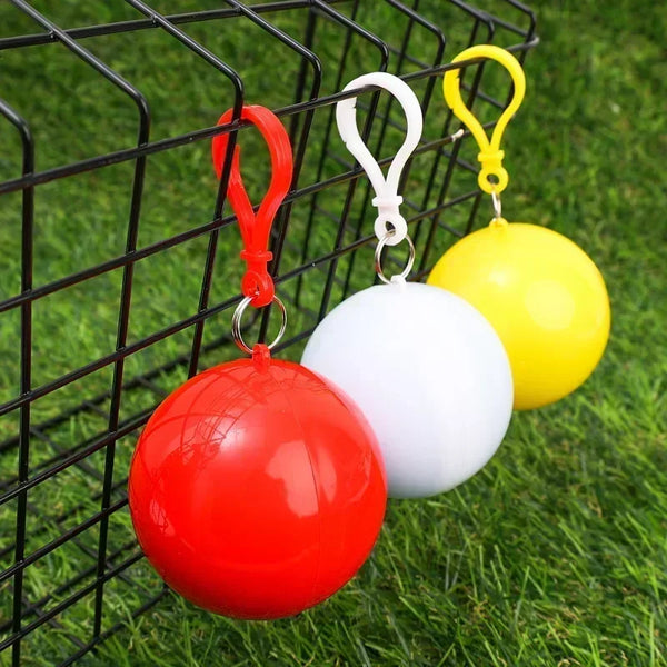 Three colorful inflatable rain ponchos, red, white, and yellow, hanging from a black wire grid.