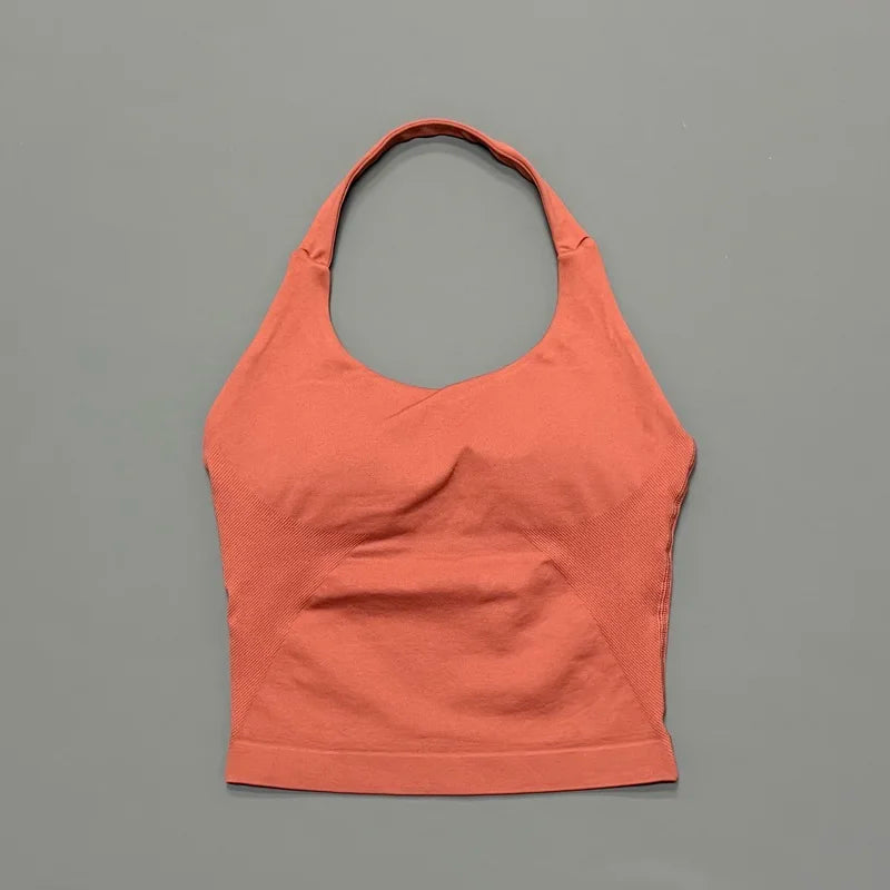 A seamless performance yoga and gym tank top in a coral orange color displayed against a gray background.
