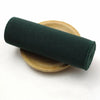 A dark green elastic band rolled up on a wooden surface.