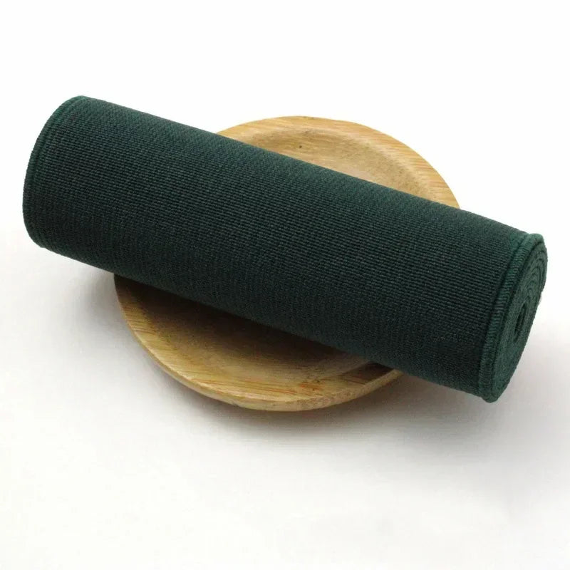 A dark green elastic band rolled up on a wooden surface.