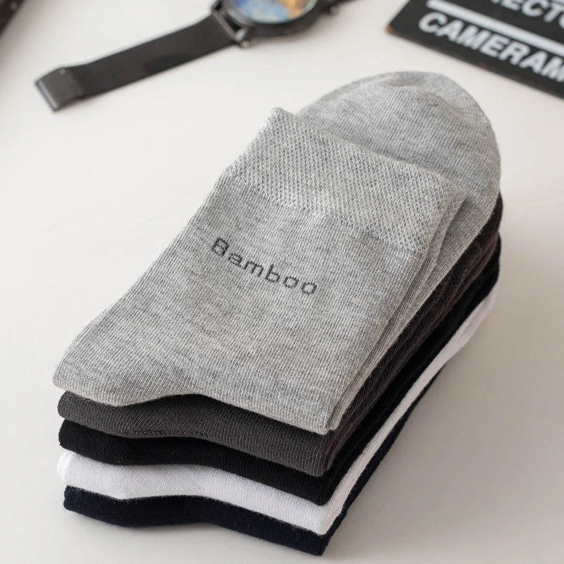 A stack of five gray, black, and white bamboo fiber socks lying on a white surface.