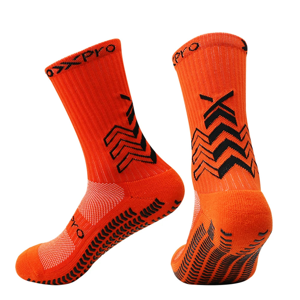 A pair of bright orange athletic sports socks with black chevron patterns.