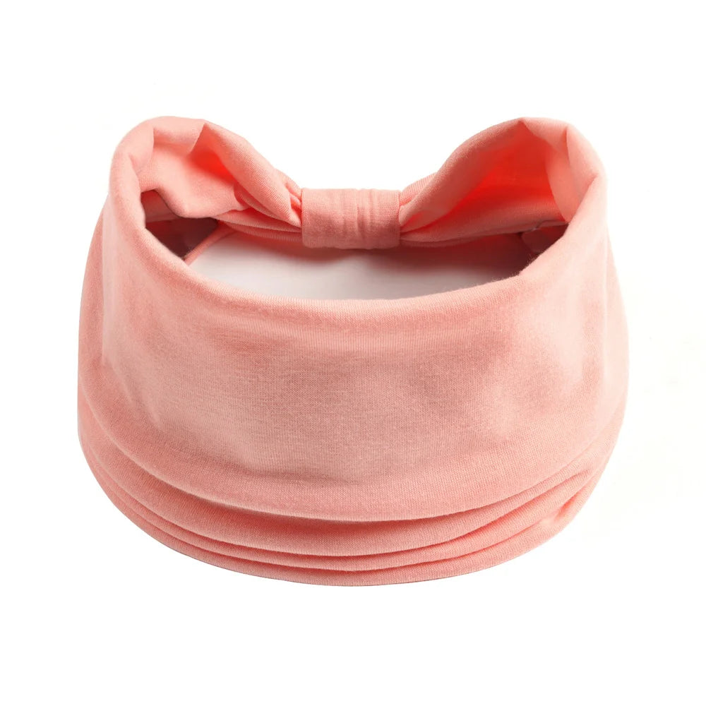 Foulard en coton boho rose corail doux noué en nœud, montré à plat.