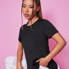 A woman models a black breathable summer yoga and fitness t-shirt in a studio setting.